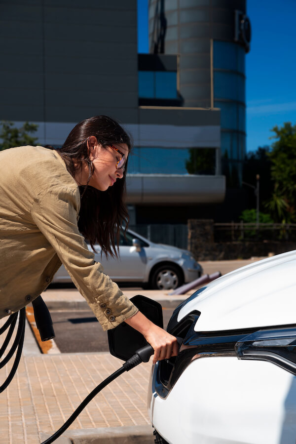 femme qui recharge sa voiture sur le parking d'une entreprise